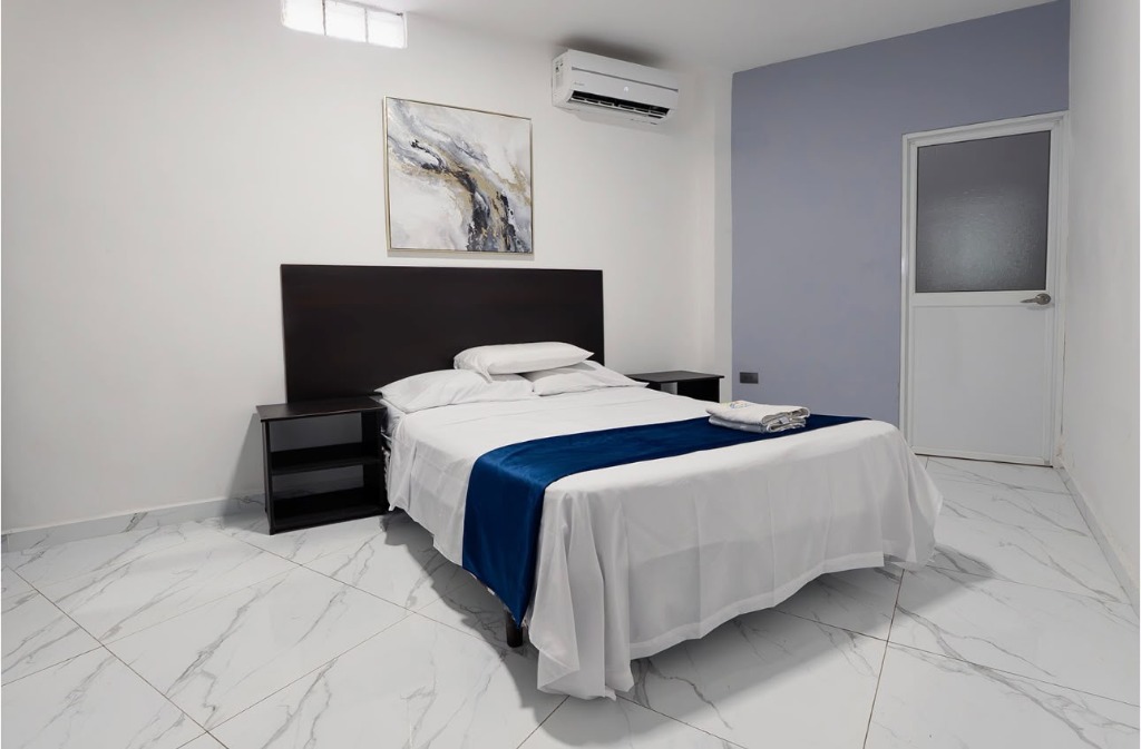 Habitación matrimonial con cama blanca y camino azul
